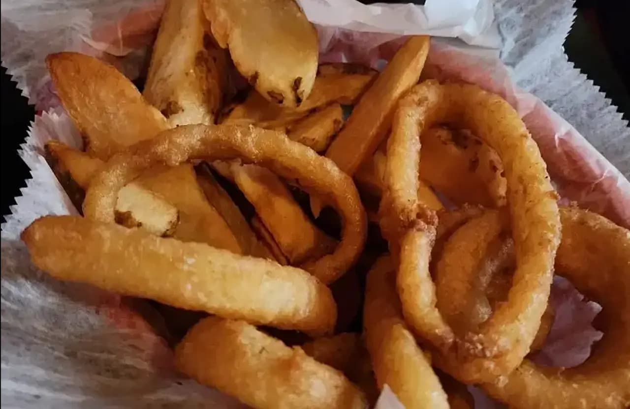 Crispy onion rings served in a basket at Torch Bar & Grill