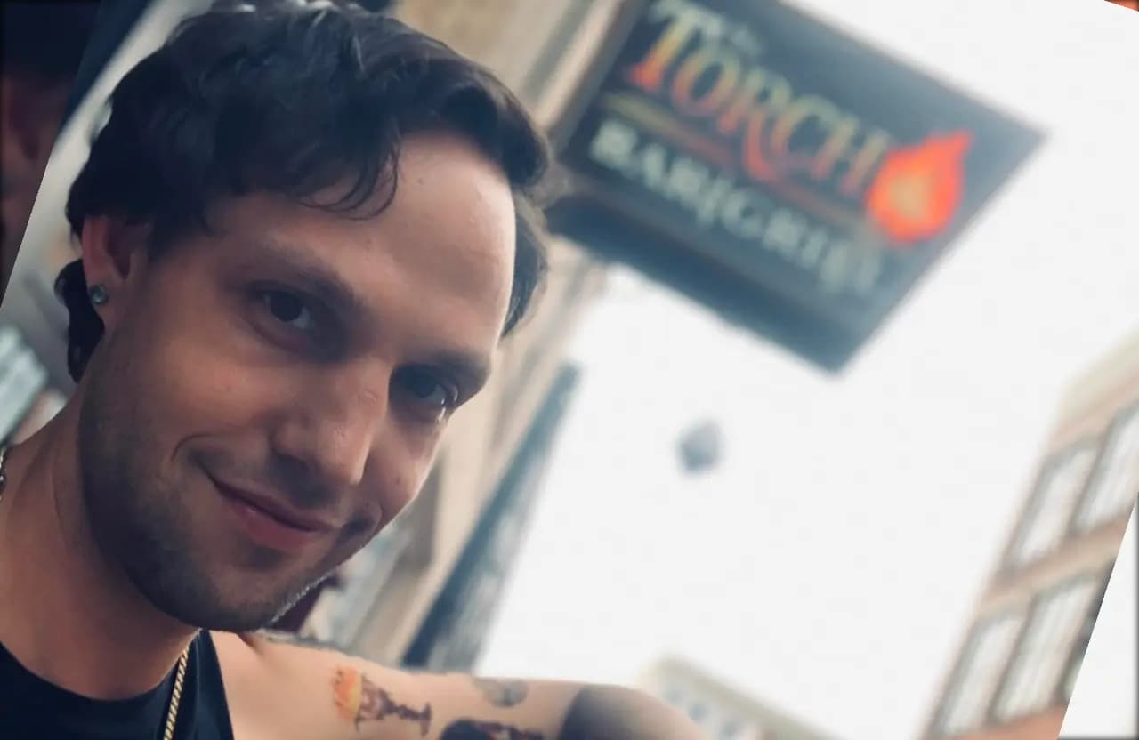 Guest smiling in front of the Torch Bar & Grill sign